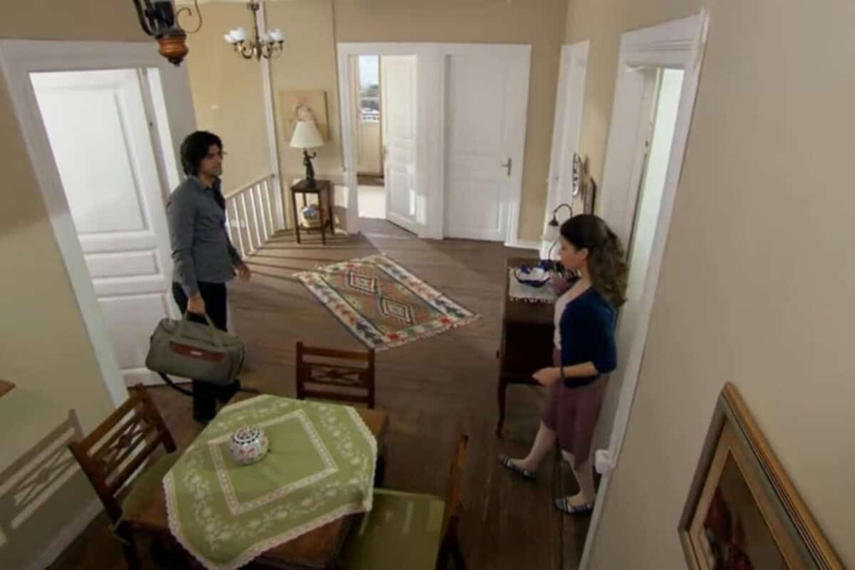 Fatmagül e Kerim em um momento de tensão, com Fatmagül demonstrando tristeza e Kerim com expressão séria