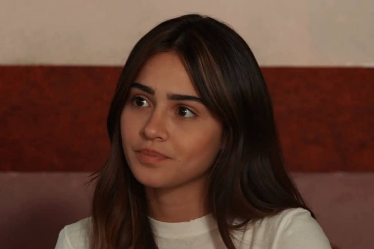 Sandra chora em uma cama de hospital, com o rosto abatido pela dor.