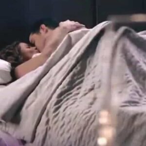 Ângela e Leonardo se abraçam em um beijo apaixonado, em um cenário romântico à luz de velas.