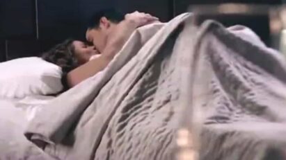 Ângela e Leonardo se abraçam em um beijo apaixonado, em um cenário romântico à luz de velas.