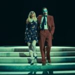Cena do trailer de "Coringa: Delírio a Dois" mostrando Coringa e Arlequina lado a lado em um ambiente sombrio e caótico