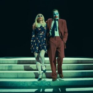 Cena do trailer de "Coringa: Delírio a Dois" mostrando Coringa e Arlequina lado a lado em um ambiente sombrio e caótico