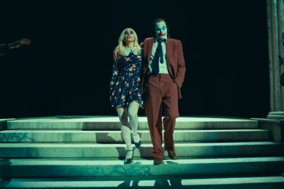 Cena do trailer de "Coringa: Delírio a Dois" mostrando Coringa e Arlequina lado a lado em um ambiente sombrio e caótico
