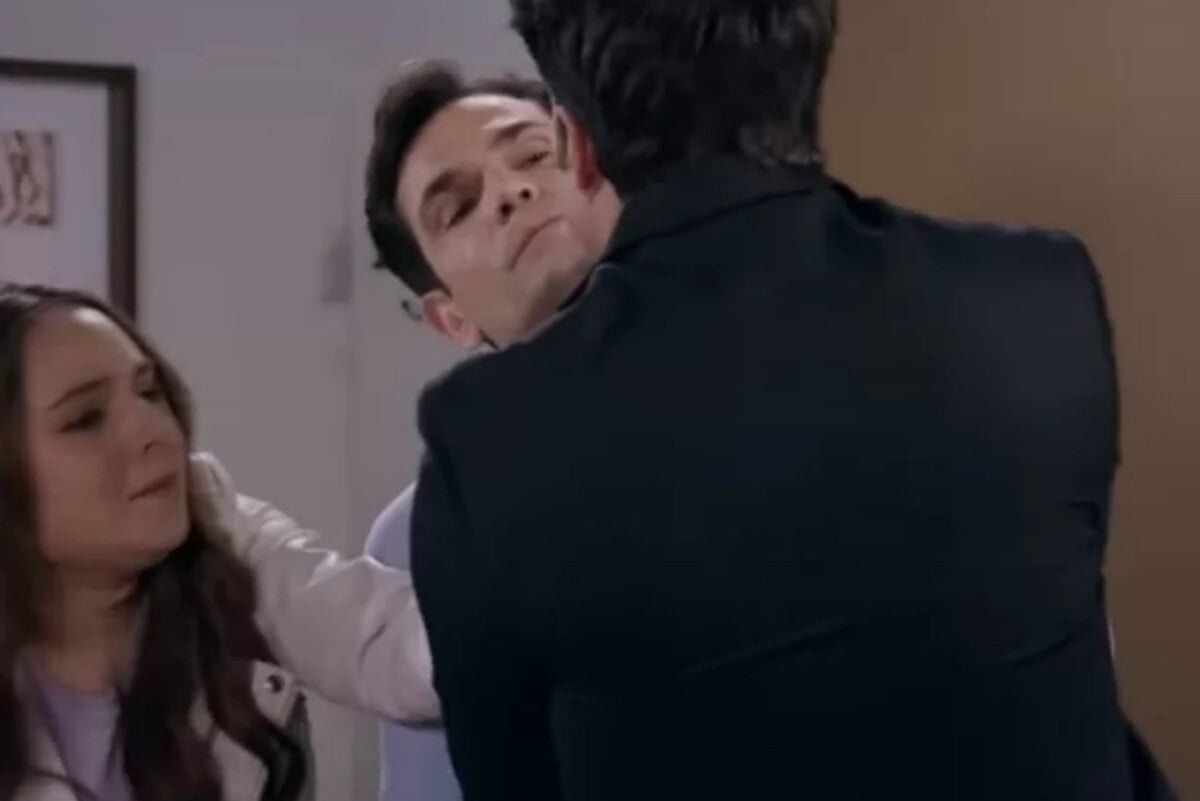 Cena de Contigo Sim mostrando Dário e Clarinha se beijando. Álvaro aparece ao fundo, entrando no quarto sem querer e com uma expressão de choque no rosto.