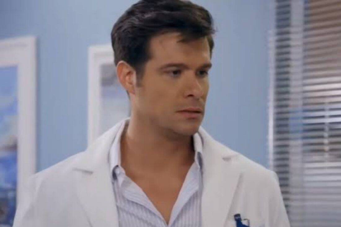 Leonardo, personagem da novela Contigo Sim, em um consultório médico, com expressão séria e mãos cruzadas, conversando com Ângela.