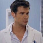 Leonardo, personagem da novela Contigo Sim, em um consultório médico, com expressão séria e mãos cruzadas, conversando com Ângela.