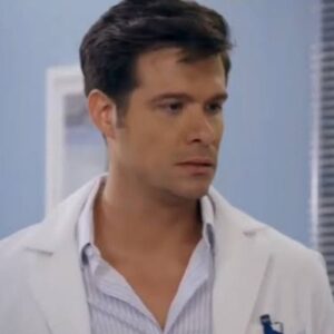 Leonardo, personagem da novela Contigo Sim, em um consultório médico, com expressão séria e mãos cruzadas, conversando com Ângela.