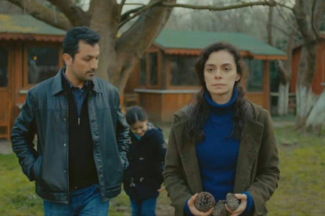 Bahar e Arif trocando olhares em um piquenique ao ar livre com as crianças, em um momento de revelação emocional