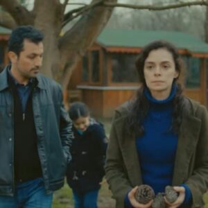 Bahar e Arif trocando olhares em um piquenique ao ar livre com as crianças, em um momento de revelação emocional