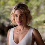 Blandina sorrindo de forma maliciosa, enquanto observa Quinota e Artur em uma situação tensa