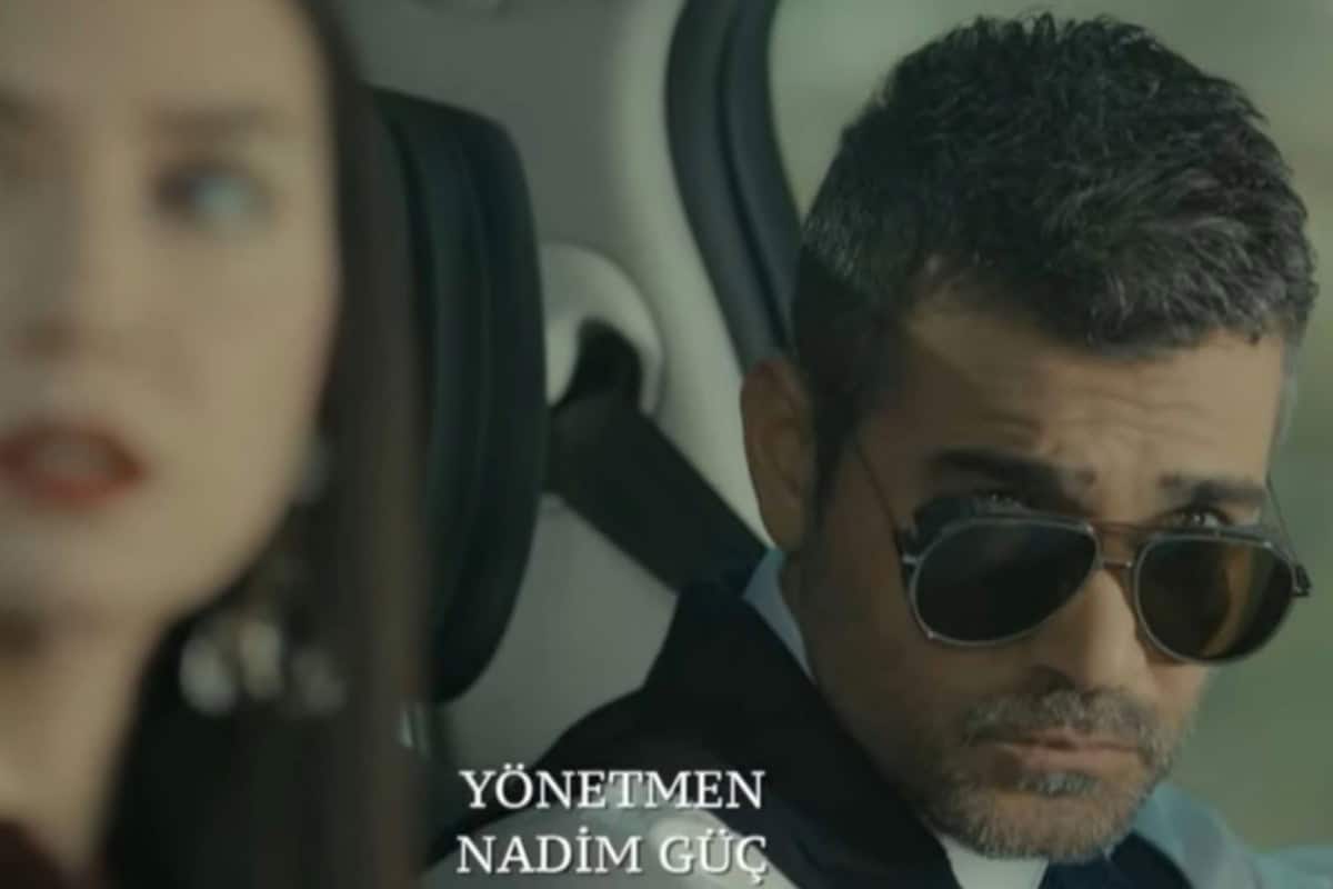 Imagem de Sarp dirigindo um carro de luxo enquanto Piril observa um ônibus lotado ao lado.