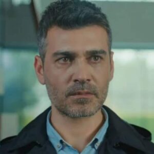 Sarp observando Julide e Suat em conversa suspeita na novela Força de Mulher