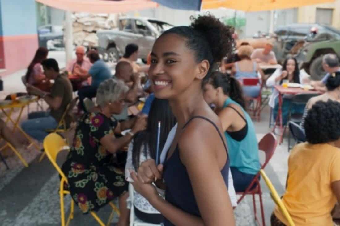 "Viola atende clientes no bar lotado, demonstrando talento culinário."