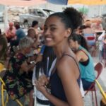 "Viola atende clientes no bar lotado, demonstrando talento culinário."