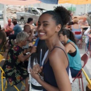 "Viola atende clientes no bar lotado, demonstrando talento culinário."