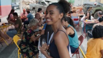 "Viola atende clientes no bar lotado, demonstrando talento culinário."