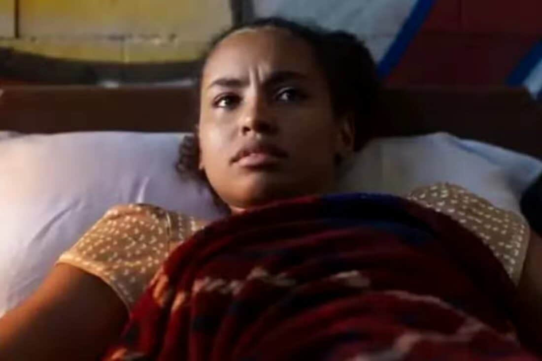 Cena da novela Mania de Você mostrando Mavi carregando Viola ferida em meio à mata.