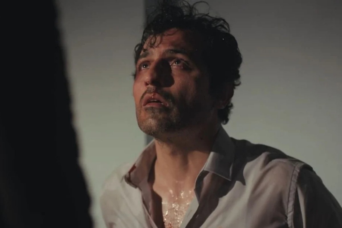 Arif amarrado em uma cadeira, com marcas de agressão no rosto.