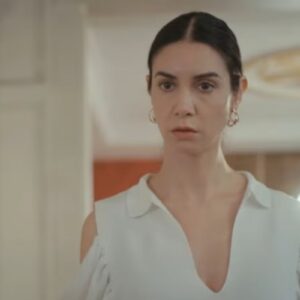 Cena da novela Força de Mulher, mostrando Piril pensativa, segurando o celular com a tela iluminada, demonstrando seu dilema.