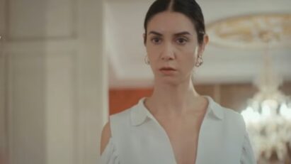 Cena da novela Força de Mulher, mostrando Piril pensativa, segurando o celular com a tela iluminada, demonstrando seu dilema.