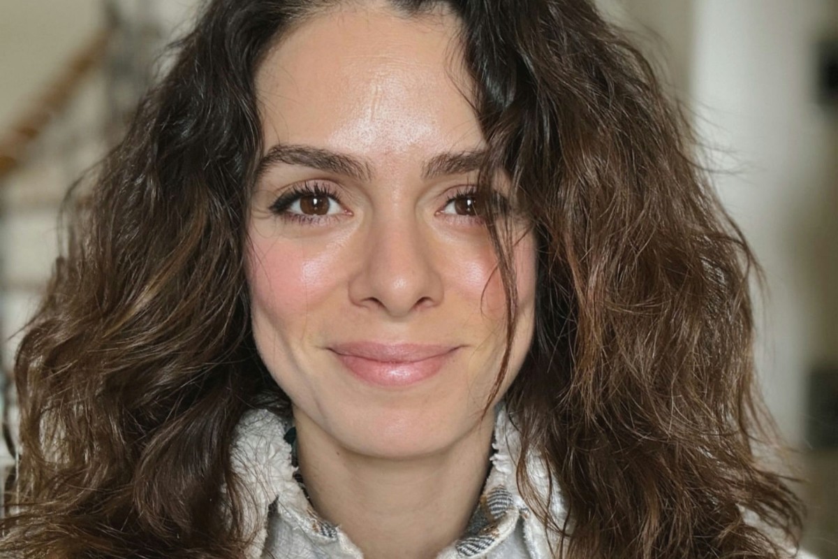 Foto de Özge Özpirinçci em um look preto, sorrindo e com um olhar expressivo.