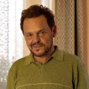 Close-up de Poliana (Matheus Nachtergaele) sorrindo em "Vale Tudo".