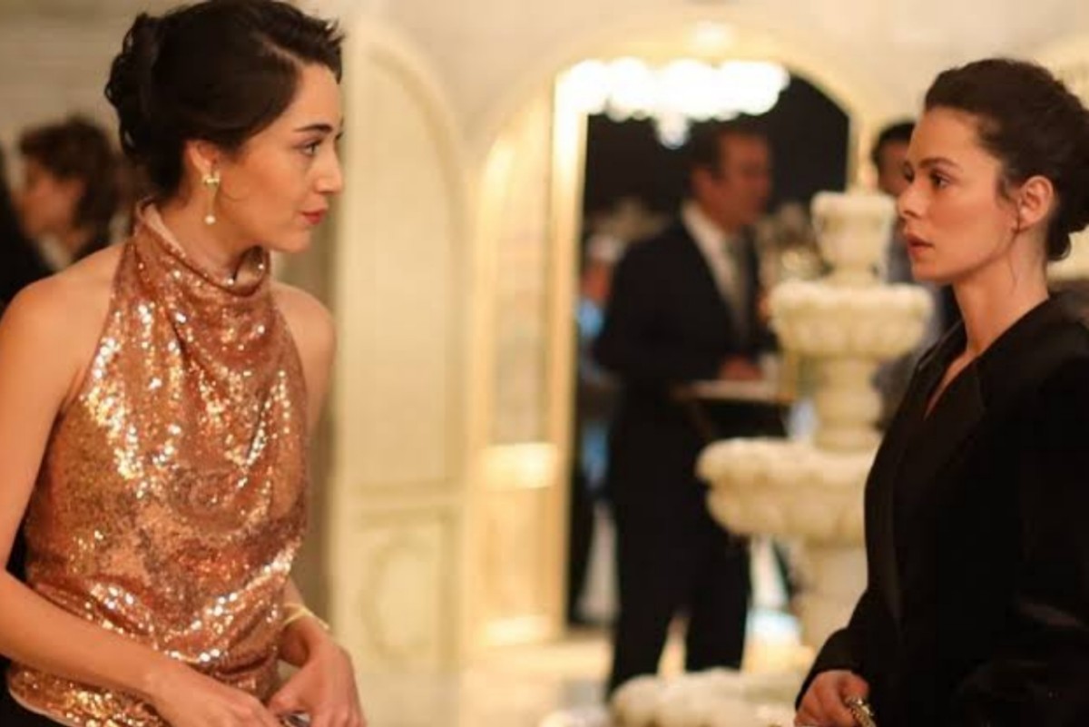 Bahar e Kismet trocando olhares tensos durante o evento em Força de Mulher, cena que revela conexão inesperada entre as personagens.