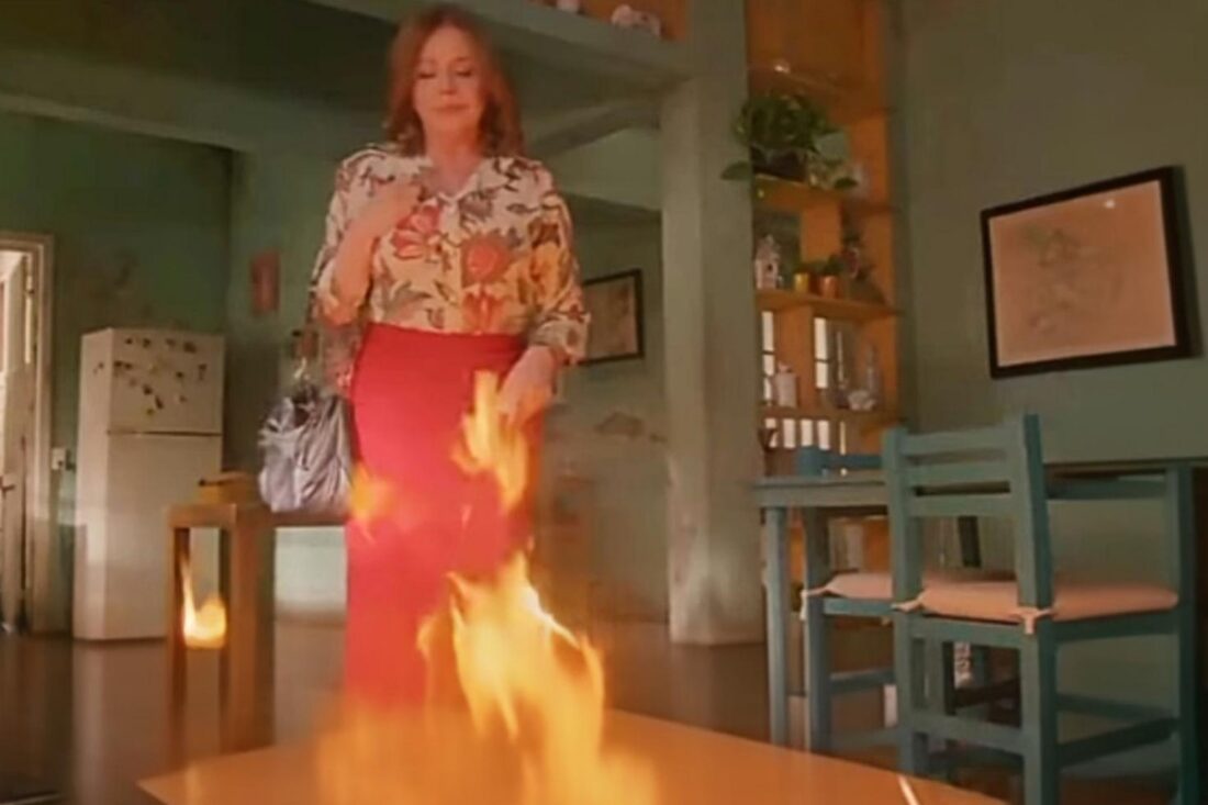 Ofélia observa o incêndio consumindo sua casa com expressão fria, enquanto Valéria e Artur correm desesperados em "As Filhas da Senhora Garcia".
