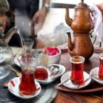 Close-up de duas xícaras de chá em forma de tulipa, cheias de chá turco, sobre uma mesa. A imagem destaca a cor da bebida e o design das xícaras.