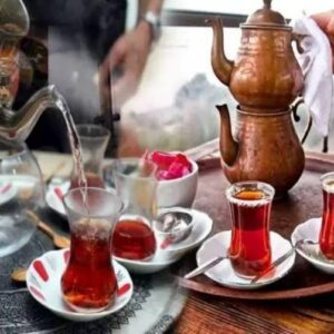 Close-up de duas xícaras de chá em forma de tulipa, cheias de chá turco, sobre uma mesa. A imagem destaca a cor da bebida e o design das xícaras.