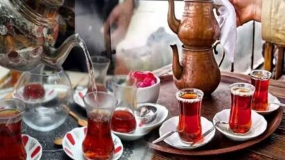 Close-up de duas xícaras de chá em forma de tulipa, cheias de chá turco, sobre uma mesa. A imagem destaca a cor da bebida e o design das xícaras.