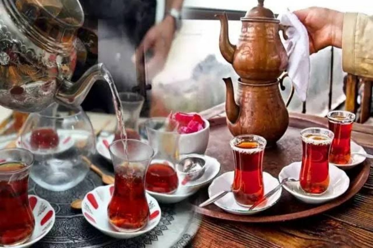 Close-up de duas xícaras de chá em forma de tulipa, cheias de chá turco, sobre uma mesa. A imagem destaca a cor da bebida e o design das xícaras.