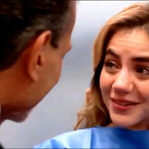 Mãe emocionada segura a mão do marido durante exame de ultrassom.”