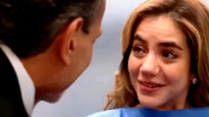 Mãe emocionada segura a mão do marido durante exame de ultrassom.”