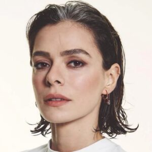 Özge Özpirinçci sorrindo em evento internacional com look natural.