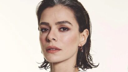 Özge Özpirinçci sorrindo em evento internacional com look natural.