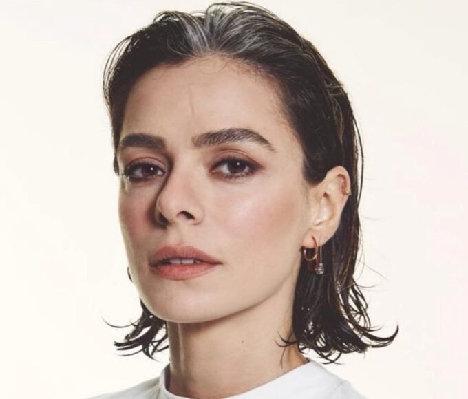 Özge Özpirinçci sorrindo em evento internacional com look natural.
