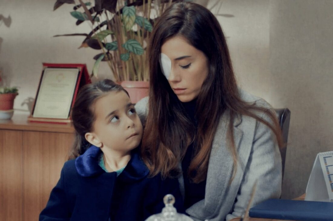 Zeynep com curativo no olho ao lado da menina Turna (Melek) e Gönul, na entrada da escola, em cena dramática da novela Mãe da Record.