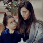 Zeynep com curativo no olho ao lado da menina Turna (Melek) e Gönul, na entrada da escola, em cena dramática da novela Mãe da Record.